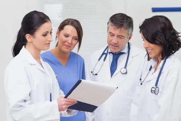 Médicas y médicos revisando juntos una historia clínica